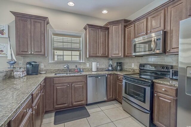 kitchen with backsplash, light tile patterned floors, appliances with stainless steel finishes, and a sink