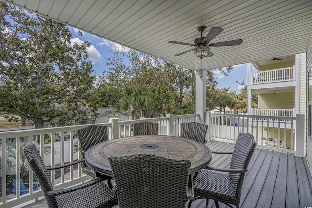 wooden deck with outdoor dining area and a ceiling fan