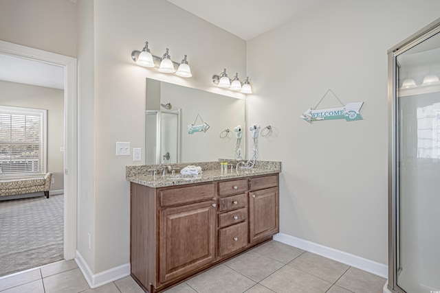 full bath with a sink, a shower with shower door, tile patterned flooring, double vanity, and baseboards