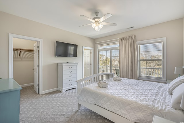 bedroom featuring ceiling fan, visible vents, baseboards, a spacious closet, and carpet