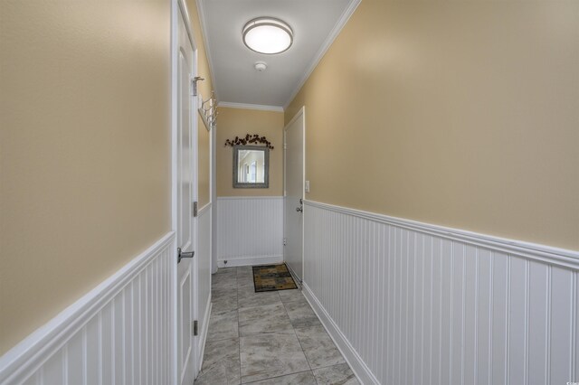 doorway to outside with a decorative wall, ornamental molding, and wainscoting