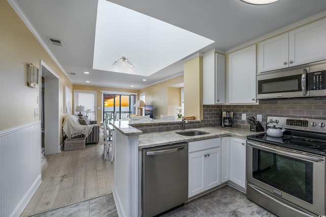 kitchen featuring light stone countertops, appliances with stainless steel finishes, a sink, open floor plan, and visible vents
