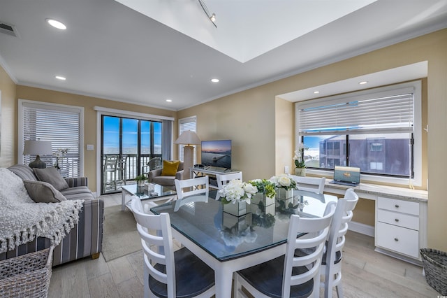 dining room with ornamental molding, a wealth of natural light, and light wood-style flooring