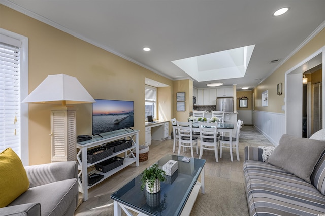 living area with crown molding, a skylight, a wainscoted wall, light wood-style floors, and recessed lighting