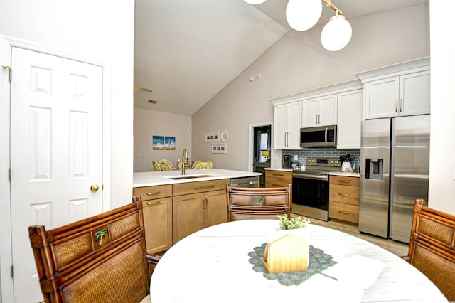 kitchen featuring a sink, high vaulted ceiling, stainless steel appliances, a peninsula, and backsplash