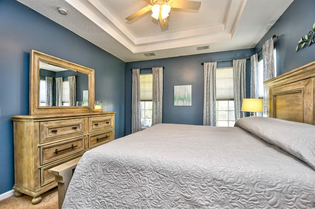 bedroom featuring visible vents, a raised ceiling, carpet floors, and multiple windows