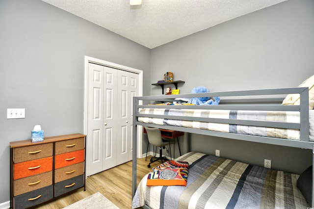 bedroom featuring ceiling fan, a closet, light wood-type flooring, and a textured ceiling