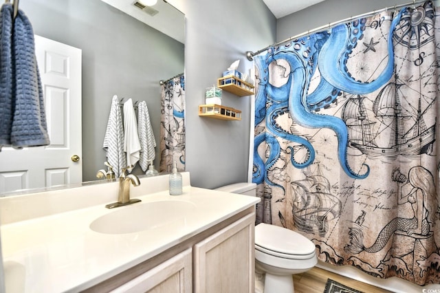 bathroom with toilet, visible vents, wood finished floors, and vanity