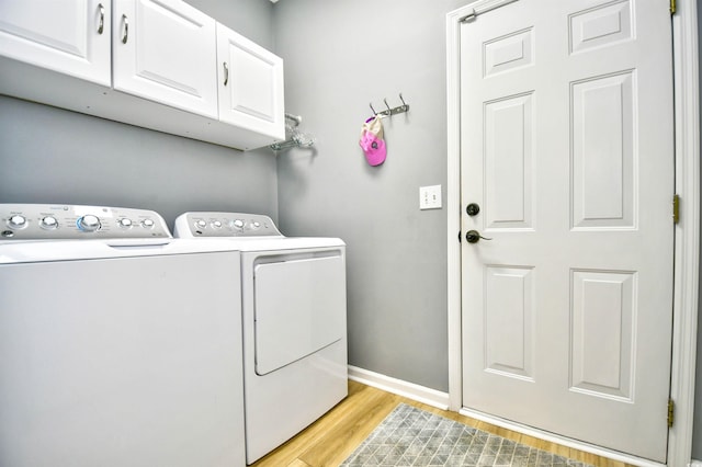 laundry room featuring cabinet space, light wood-style floors, baseboards, and washer and dryer