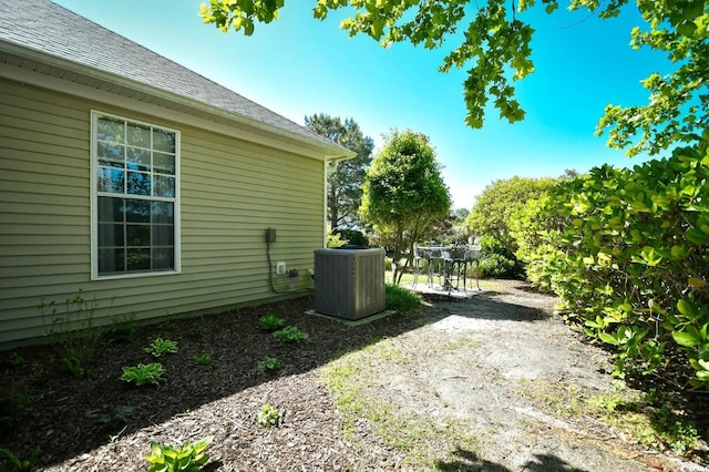 view of property exterior with central AC, a shingled roof, and a patio area
