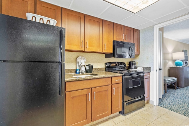 kitchen featuring brown cabinets, a sink, light tile patterned floors, and black appliances
