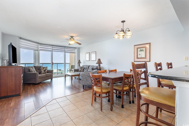 dining space with light wood-style flooring and ceiling fan with notable chandelier