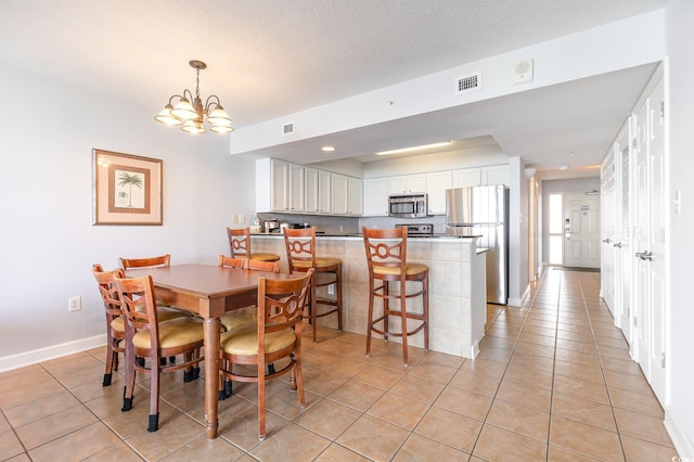 dining area featuring baseboards, a notable chandelier, visible vents, and light tile patterned floors