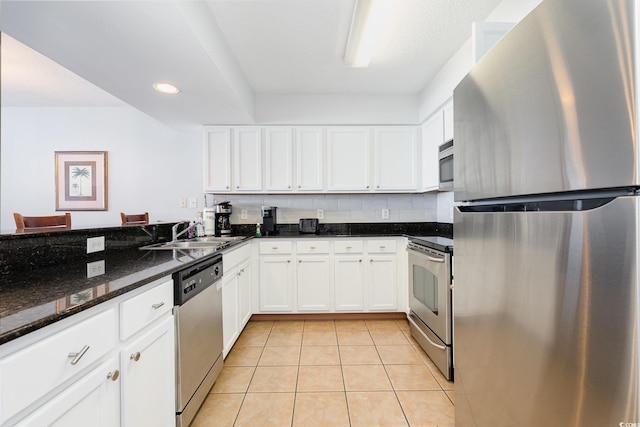 kitchen featuring a sink, light tile patterned floors, stainless steel appliances, and white cabinetry