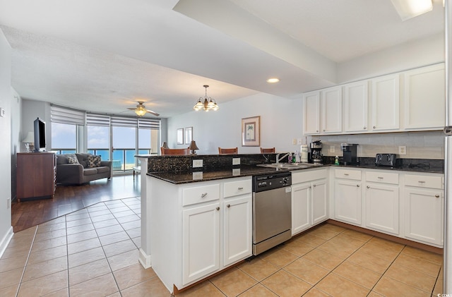 kitchen with stainless steel dishwasher, a peninsula, light tile patterned flooring, white cabinetry, and a sink