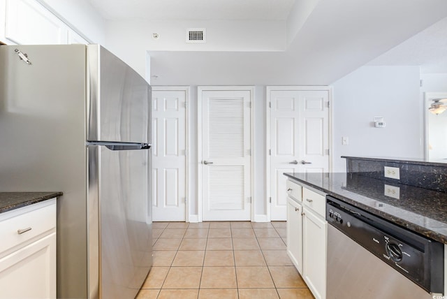 kitchen featuring visible vents, white cabinetry, dark stone countertops, light tile patterned floors, and stainless steel appliances
