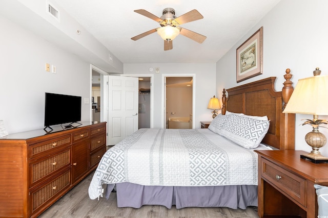 bedroom featuring ceiling fan, visible vents, wood finished floors, a closet, and connected bathroom