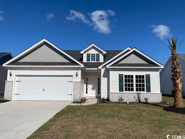 422 Lifestyle Ct, Surfside Beach, SC 29575 - craftsman house with brick siding, a garage, driveway, a front lawn, and roof with shingles