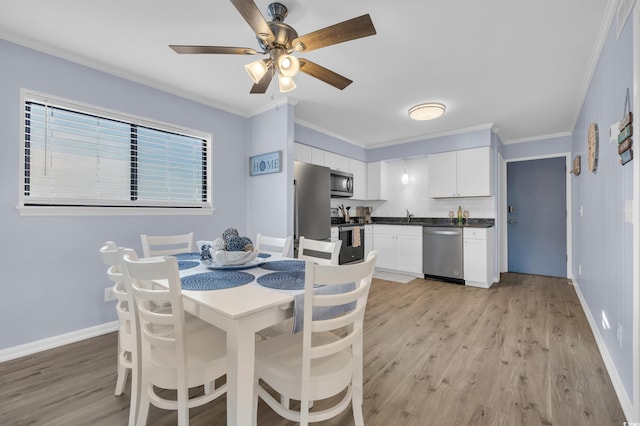 dining room with crown molding, baseboards, a ceiling fan, and light wood finished floors