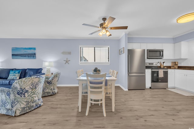 dining space featuring baseboards, ornamental molding, light wood finished floors, and a ceiling fan