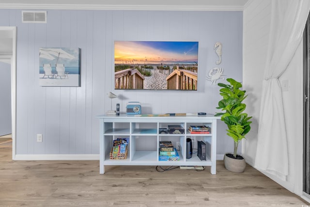 interior details featuring crown molding, baseboards, visible vents, and wood finished floors