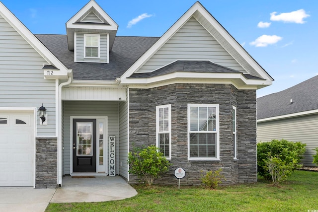 doorway to property featuring a lawn, a shingled roof, and stone siding