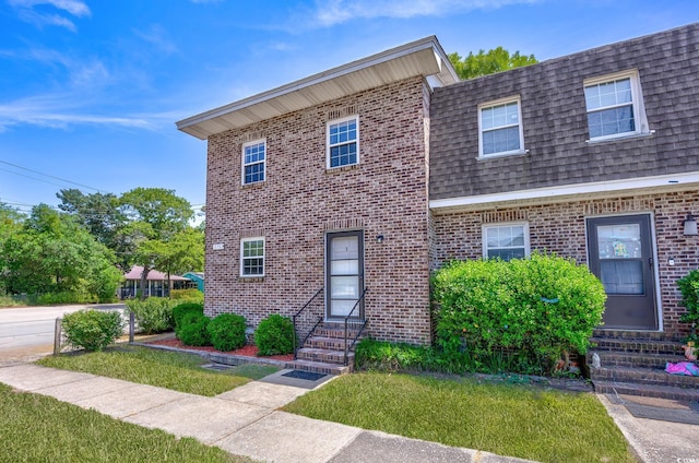 view of front of home with entry steps, a shingled roof, mansard roof, and brick siding