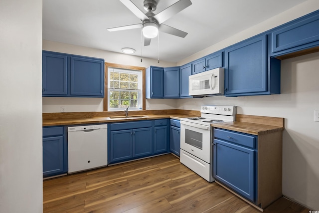 kitchen with white appliances, a sink, butcher block counters, and blue cabinets