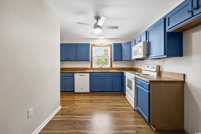 kitchen with butcher block countertops, blue cabinets, a sink, and white appliances