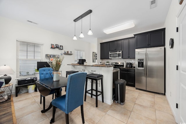 903 Ocean Pines Ct, North Myrtle Beach, SC 29582 - kitchen with stainless steel appliances, tasteful backsplash, a breakfast bar, dark cabinetry, and hanging light fixtures