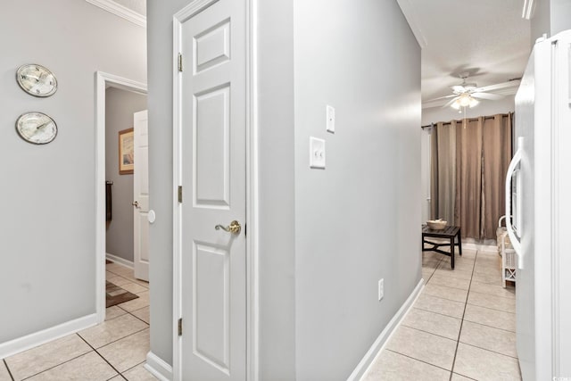 corridor with baseboards, ornamental molding, and light tile patterned floors