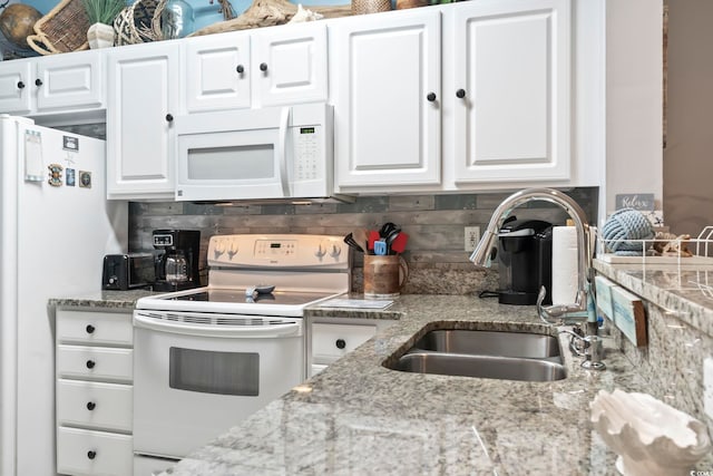 kitchen with white appliances, white cabinets, light stone counters, a sink, and backsplash