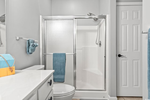 bathroom with vanity, a shower stall, and toilet