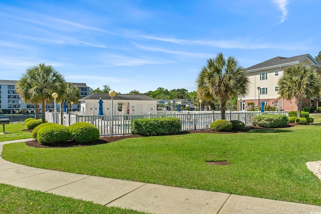 view of home's community with a yard and fence