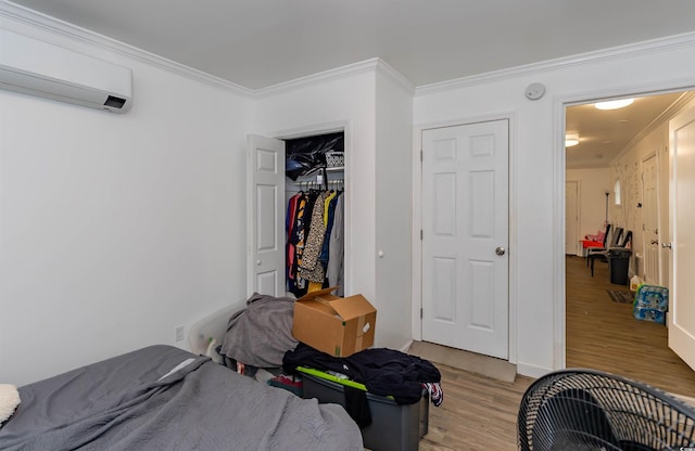 bedroom with light wood-type flooring, ornamental molding, a wall mounted air conditioner, and a closet
