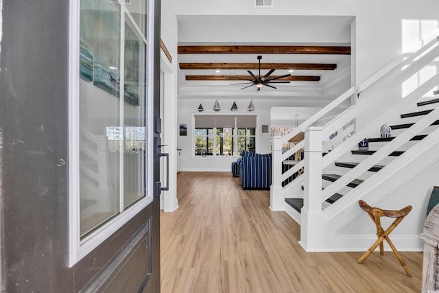 foyer entrance with ceiling fan, baseboards, light wood-type flooring, beamed ceiling, and stairway