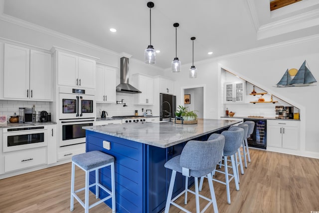 kitchen featuring decorative backsplash, a breakfast bar, beverage cooler, wall chimney exhaust hood, and white double oven