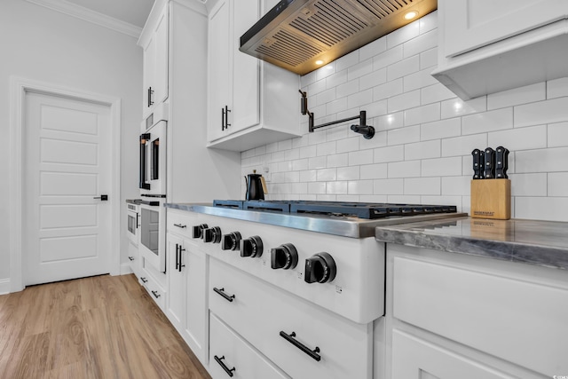 kitchen with crown molding, decorative backsplash, white cabinets, and custom range hood
