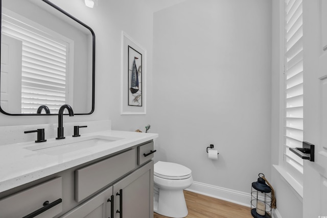 bathroom featuring vanity, baseboards, wood finished floors, and toilet