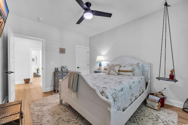 bedroom with baseboards, ceiling fan, and light wood-style flooring