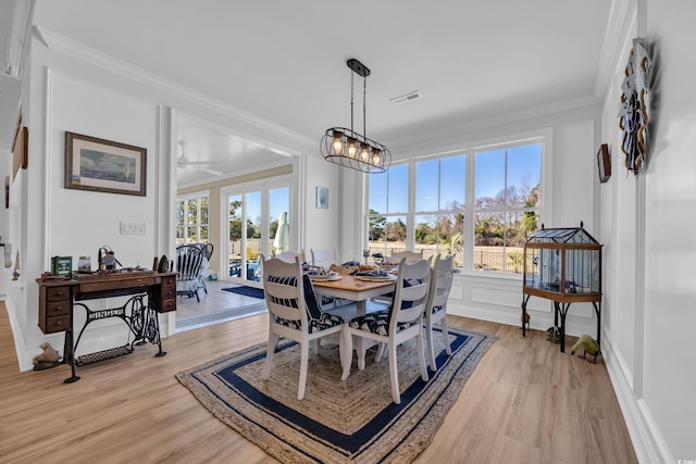 dining space featuring a ceiling fan, visible vents, light wood-type flooring, baseboards, and ornamental molding