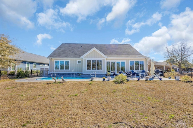 back of property featuring fence, board and batten siding, a fenced in pool, a patio area, and a yard