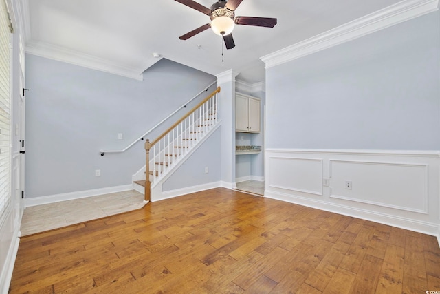 unfurnished living room with stairs, ceiling fan, ornamental molding, and light wood-style floors