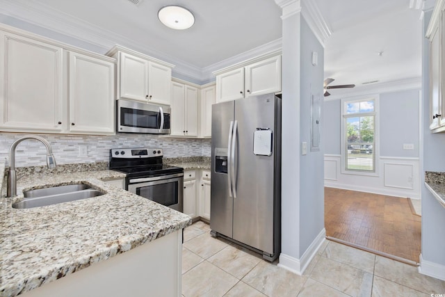 kitchen featuring crown molding, light stone countertops, a sink, stainless steel appliances, and tasteful backsplash