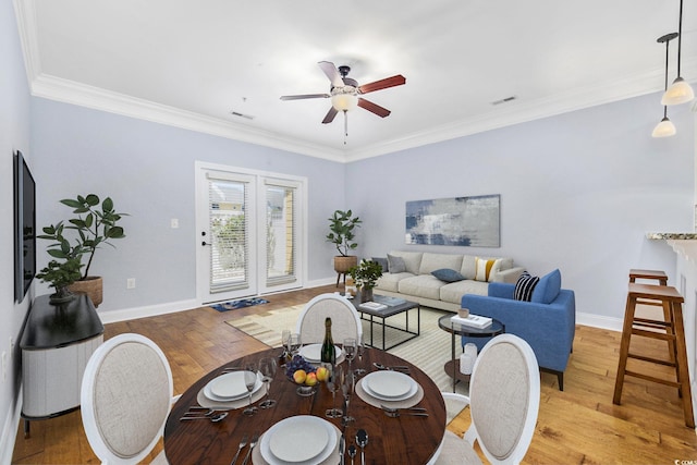 living room featuring visible vents, ornamental molding, baseboards, light wood-type flooring, and a ceiling fan