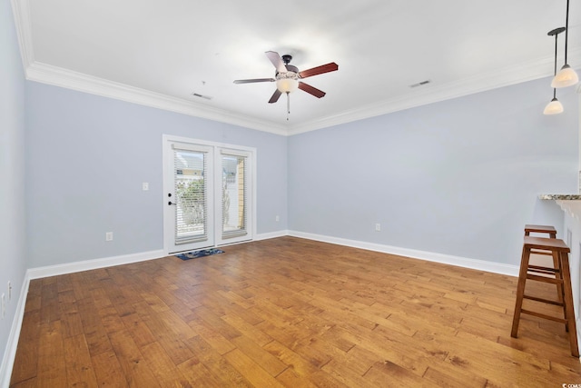 empty room featuring ceiling fan, ornamental molding, baseboards, and wood finished floors