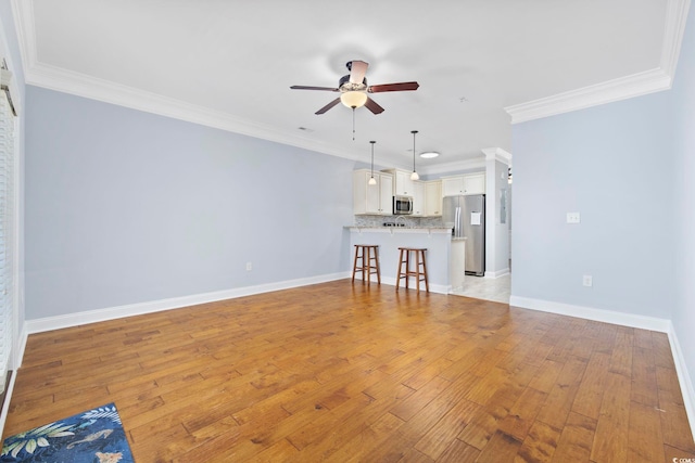 unfurnished living room with crown molding, baseboards, and ceiling fan