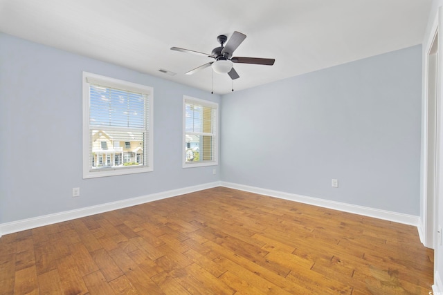 spare room with baseboards, a ceiling fan, wood finished floors, and visible vents