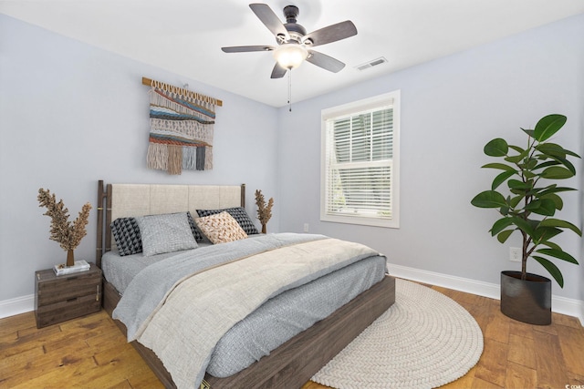 bedroom with baseboards, ceiling fan, wood-type flooring, and visible vents