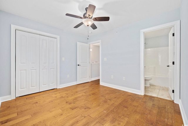 unfurnished bedroom with light wood-type flooring, baseboards, ensuite bath, and a closet